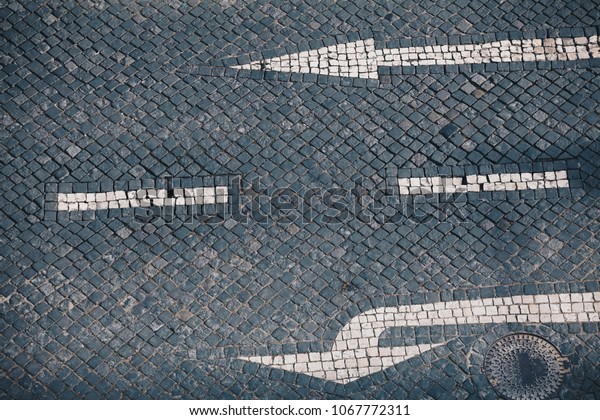 Direction arrow and street sign on handmade stone\
pavement in Lisbon - Traditional Portuguese handmade mosaic\
background - Cobble stone\
street