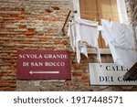 Direction sign on street pointing towards scuola grande di san rocco