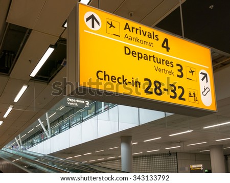 Direction signs and escalators in terminal of Schiphol Amsterdam Airport, Netherlands