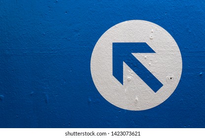 Directional arrow on a blue wall pointing upwards and left. - Shutterstock ID 1423073621