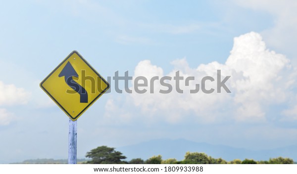 Directional arrow, reverse turn left sign on\
pole isolated with cloudy bluesky\
background.