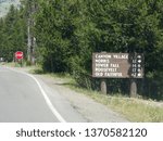 Directional sign on the roadside with directions to Canyon Village, Norris, Tower Fall, Roosevelt and Old Faithful at Yellowstone National Park in Wyoming.