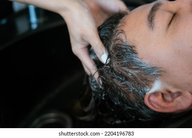 Directly Above Asian Male Lying Down For Hair Wash At Hair Salon With Eyes Closed