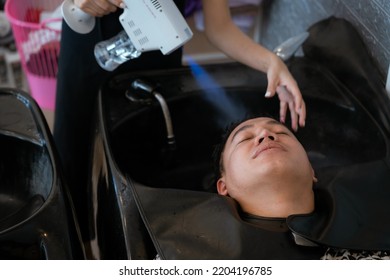 Directly Above Asian Male Lying Down For Hair Wash At Hair Salon With Eyes Closed