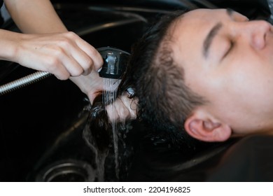 Directly Above Asian Male Lying Down For Hair Wash At Hair Salon With Eyes Closed