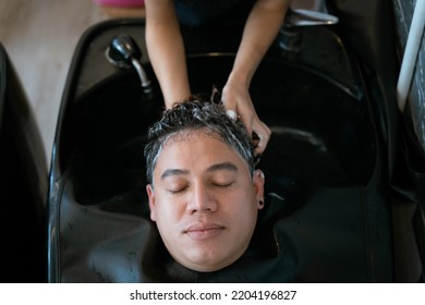 Directly Above Asian Male Lying Down For Hair Wash At Hair Salon With Eyes Closed