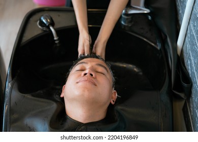 Directly Above Asian Male Lying Down For Hair Wash At Hair Salon With Eyes Closed