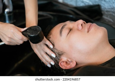 Directly Above Asian Male Lying Down For Hair Wash At Hair Salon With Eyes Closed