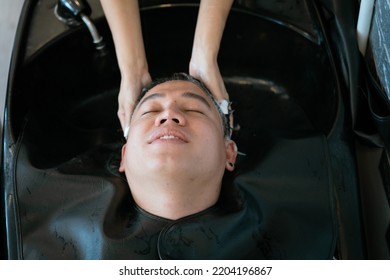 Directly Above Asian Male Lying Down For Hair Wash At Hair Salon With Eyes Closed