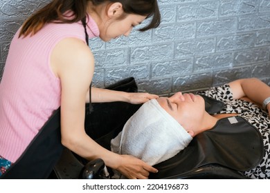 Directly Above Asian Male Lying Down For Hair Wash At Hair Salon With Eyes Closed