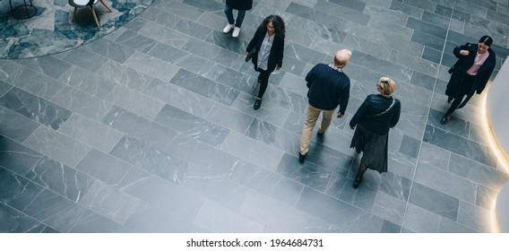 Directly Above Shot Of Business People Walking Through A Office Hallway. People In A Lobby Of Commercial Building.