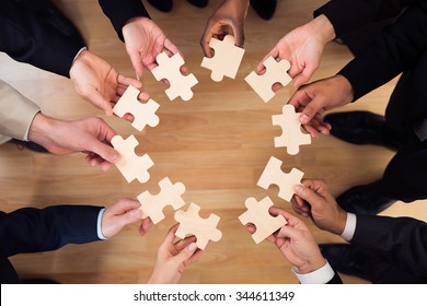 Directly above shot of business people joining jigsaw puzzle pieces in office - Shutterstock ID 344611349