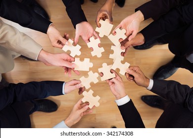 Directly above shot of business team joining jigsaw pieces in office - Shutterstock ID 342174308