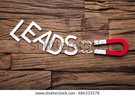 Directly above shot of magnet pulling leads letter blocks on wooden table