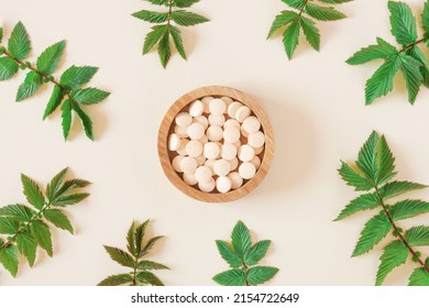 Directly Above Shot Of Pills and green leaves. Tablets in wooden bowl on beige neutral colors background. Homeopathic medicine. Organic medical capsules with herbal plant. Table top view. Copy space. - Shutterstock ID 2154722649