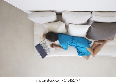 Directly Above Shot Of Woman Using Laptop On Couch In Living Room