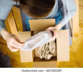 Directly Above View Of Curious Woman Unboxing In The Living Room New Delivery Of E-commerce Ordered Goods Via Internet - Plastic Bubble Warping Protection Film Cardboard Box