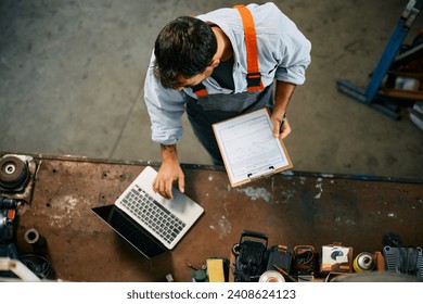 Directly above view of a mechanic using laptop while working at repair shop. - Powered by Shutterstock