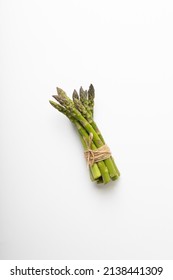 Directly above view of raw green asparagus tied with string by copy space on white background. unaltered, food, healthy eating and organic concept.