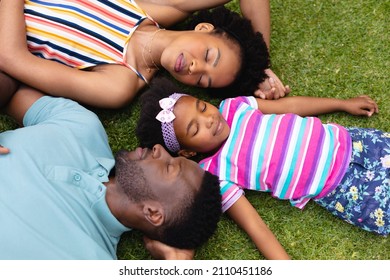 Directly above view of tired african american family sleeping together on grass at garden. family, love and togetherness concept, unaltered.