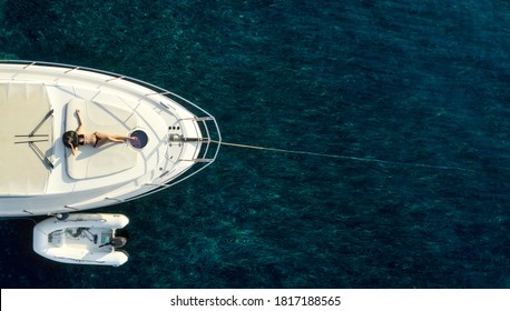 Directly above view at white luxury yacht with woman in swimsuit and hat laying on. Copy space