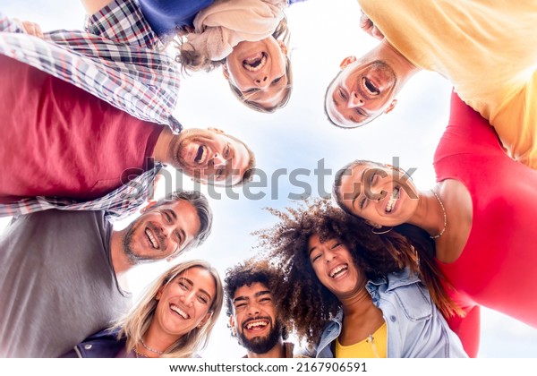 directly below portrait of interracial group of\
friends posing in the street outdoors laughing and having fun.\
diverse people celebrating life together enjoying happy holidays.\
lifestyle concept
