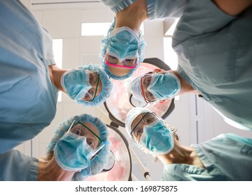 Directly Below Portrait Of Medical Team Wearing Masks And Scrubs In Operation Room