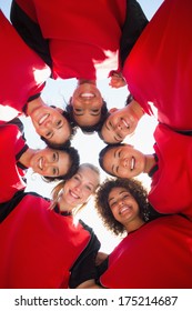 Directly Below Shot Of Happy Female Soccer Team Forming Huddle Against Clear Sky