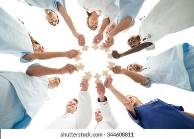 Directly below shot of medical team joining jigsaw pieces in huddle against white background - Powered by Shutterstock