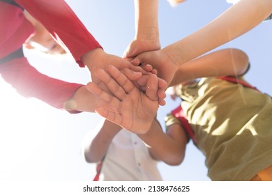 Directly below shot of multiracial elementary schoolboys stacking hands while standing against sky. unaltered, childhood, education, together, sunny and back to school concept. - Powered by Shutterstock