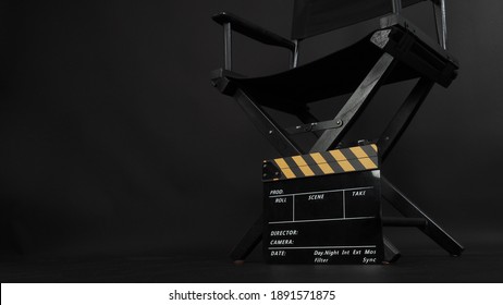 Director chair and Clapper board or movie slate use in video production or film and cinema industry. It's put on black blackground.
