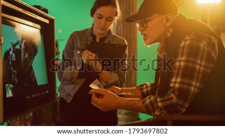 Director Looks at Display and Compares to Storyboard while Shooting Blockbuster Movie. Green Screen Scene with Actor Wearing Motion Caption Suit. Studio Set Professional Crew Doing High Budget Movie