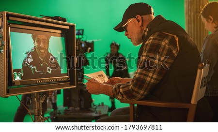 Director Looks at Display and Compares to Storyboard while Shooting Blockbuster Movie. Green Screen Scene with Actor Wearing Motion Caption Suit. Film Studio Professional Crew Doing High Budget Movie