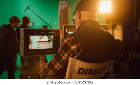 Director Looks at Display Controls Shooting History Movie. Green Screen CGI Scene with Actors Wearing Renaissance Costumes. Big Film Studio Professional Crew Shooting High Budget Movie