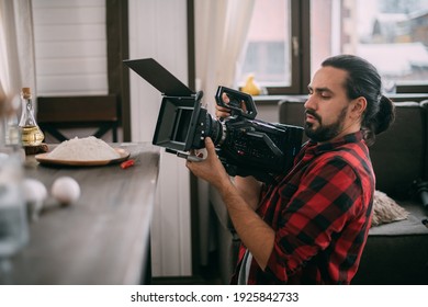 Director of photography with a camera in his hands on the set. Professional videographer at work on filming a movie, commercial or TV series. Filming process indoors, studio