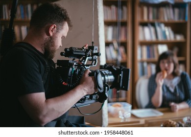 Director of photography with a camera in his hands on the set. Professional videographer at work on filming a movie, commercial or TV series. Filming process indoors, studio - Shutterstock ID 1958448061