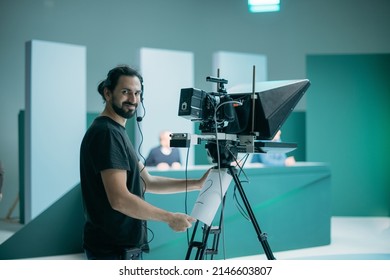 Director Of Photography With A Camera In His Hands On The Set. Professional Videographer At Work On Filming A Movie, Commercial Or TV Series. Filming Process Indoors, Studio