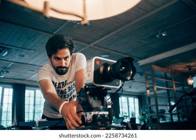Director of photography with a camera in his hands on the set. Professional videographer at work on filming a movie, commercial or TV series. Filming process indoors, studio - Shutterstock ID 2258734261