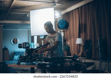 Director of photography with a camera in his hands on the set. Professional videographer at work on filming a movie, commercial or TV series. Filming process indoors, studio - Shutterstock ID 2267234833