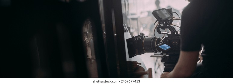 Director of photography with a camera in his hands on the set. Professional videographer at work on filming a movie, commercial or TV series. Filming process indoors, studio