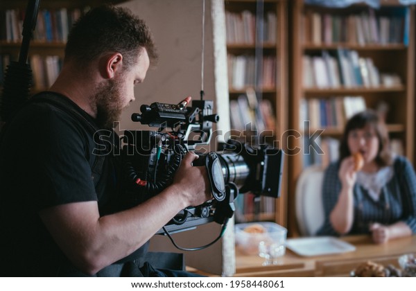 Director of photography\
with a camera in his hands on the set. Professional videographer at\
work on filming a movie, commercial or TV series. Filming process\
indoors, studio