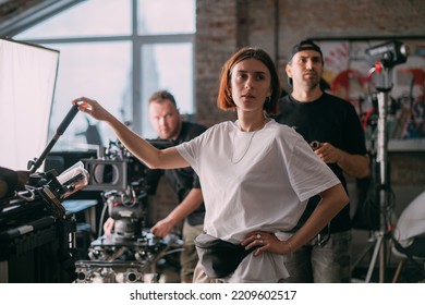 The director of photography is a woman behind a video camera on the set. A professional videographer at work on the filming of a movie, commercial or TV series. Filming process indoors, studio