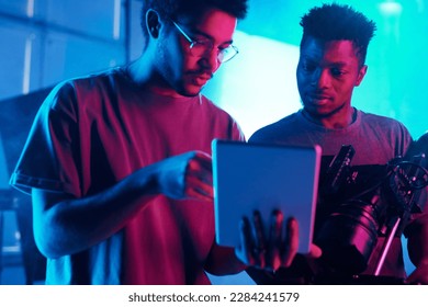 Director showing theme of shooting on digital tablet to photographer while they working in team in production studio - Powered by Shutterstock