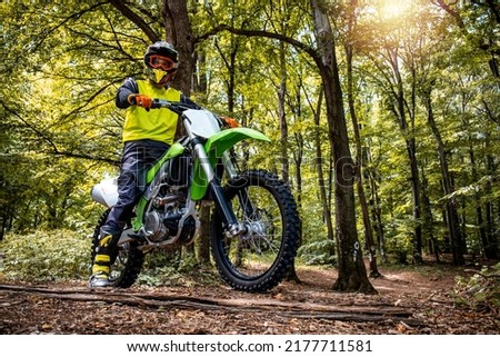 Dirt bike rider enjoying off road ride through the forest and rough terrain.