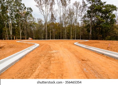 Dirt graded for roads in a residential construction site with new concrete curbs - Powered by Shutterstock