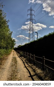 Dirt Path Partly In The Shade Casted By A Hedge And Split By A Wooden Fence In The Countryside