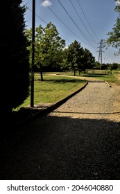 Dirt Path Partly In The Shade Casted By A Hedge And Split By A Wooden Fence In The Countryside