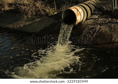 Dirt pipe releasing water into stream. Sewage pipe to river.
