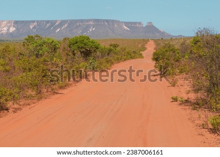 A dirt road in the Cerrado (brazilian tropical savanna) at the Jalapao State Park, with Espirito Santo mountain ridge in the background. State of Tocantins, Brazil.