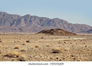 A Dirt Road Cuts Through The Barren, Desolate Landscape Of Namibia.